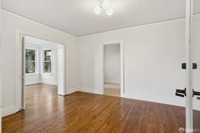 unfurnished room featuring crown molding, baseboards, and wood finished floors