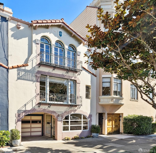 mediterranean / spanish-style house featuring an attached garage, driveway, a tile roof, and stucco siding