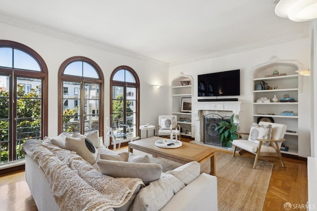 living room with ornamental molding, a high end fireplace, and built in features