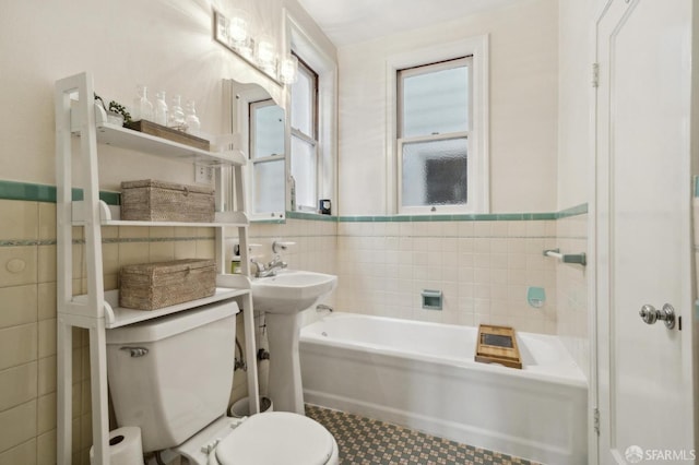 full bath with toilet, a bathing tub, tile walls, and wainscoting