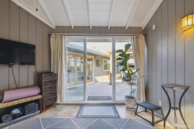 doorway to outside featuring french doors, plenty of natural light, vaulted ceiling with beams, and wood walls