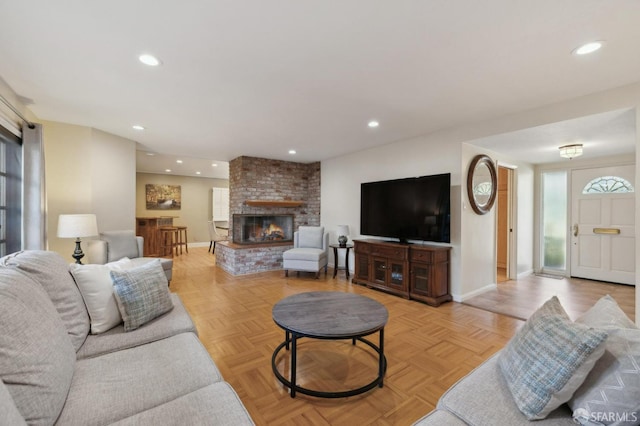 living room with a brick fireplace and light parquet floors