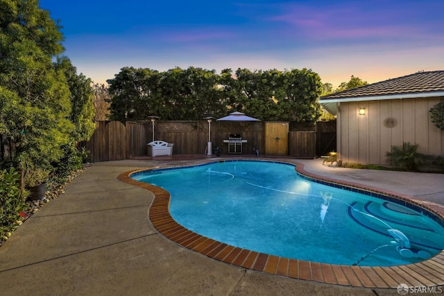 pool at dusk with a patio area