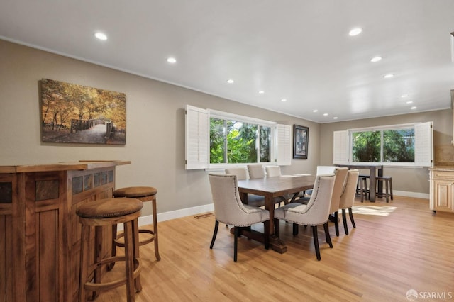 dining area with indoor bar, a healthy amount of sunlight, and light hardwood / wood-style floors