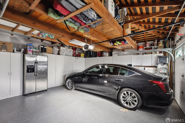 garage with a garage door opener and stainless steel fridge