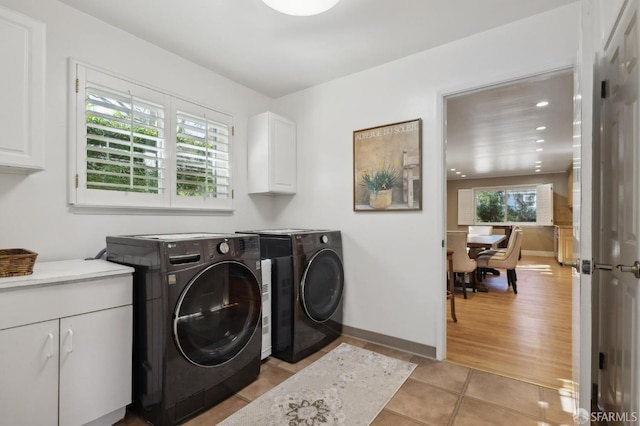 laundry room with cabinets, light tile patterned floors, and washing machine and clothes dryer