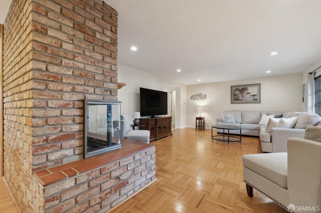 living room with a brick fireplace and light parquet floors