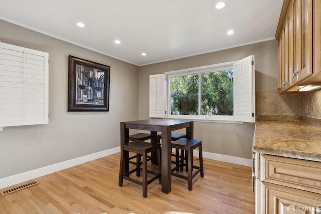 dining room with crown molding and light wood-type flooring