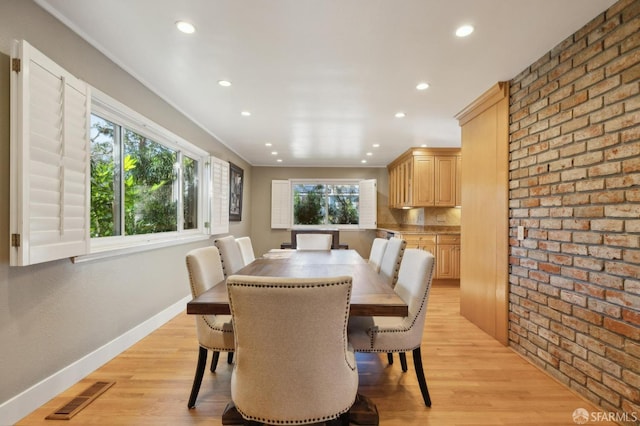 dining area with brick wall and light wood-type flooring