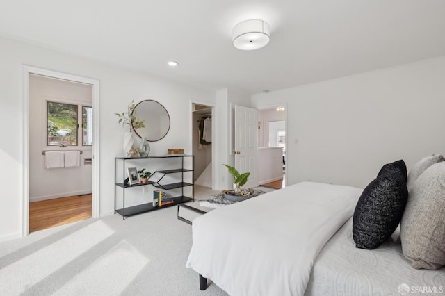 carpeted bedroom featuring recessed lighting, a walk in closet, and baseboards