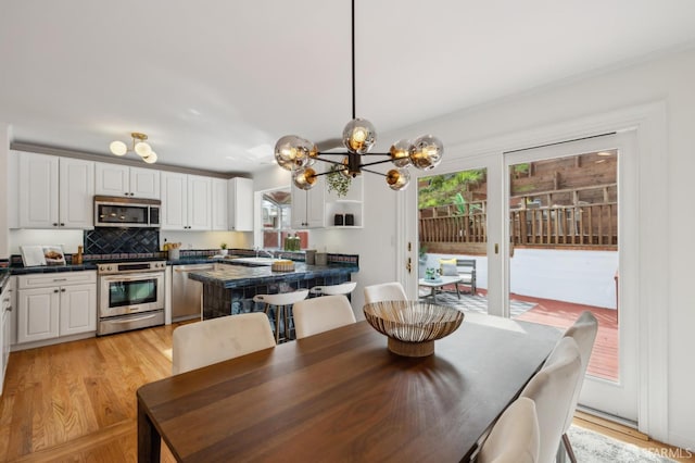 dining area with light wood-style floors and an inviting chandelier