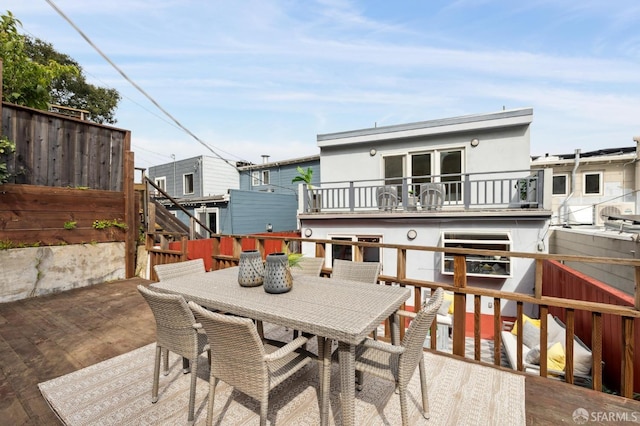 exterior space featuring outdoor dining area, fence, a balcony, and stucco siding