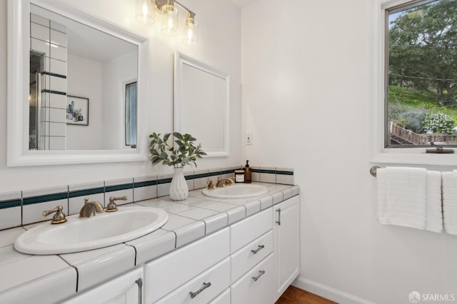 bathroom with double vanity, baseboards, and a sink