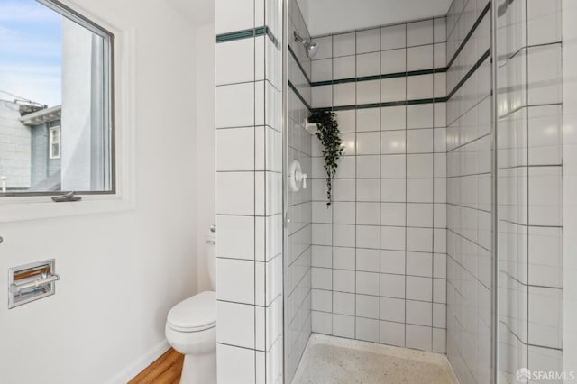 bathroom featuring tiled shower and toilet