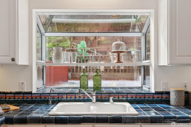 room details featuring white cabinets and tile countertops