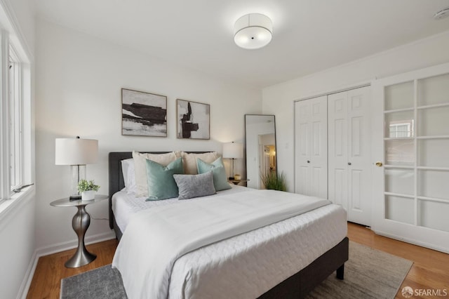 bedroom with a closet, wood finished floors, and baseboards