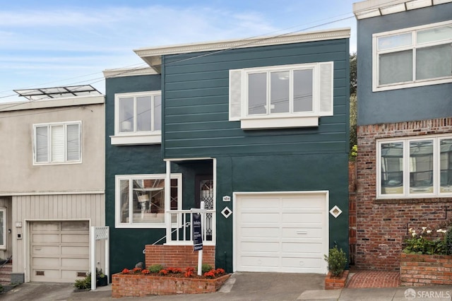 multi unit property featuring a garage, concrete driveway, and stucco siding