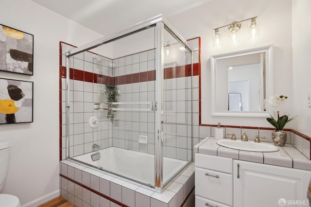 bathroom with tiled shower / bath combo, vanity, toilet, and baseboards