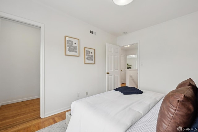 bedroom with light wood-type flooring, visible vents, and baseboards