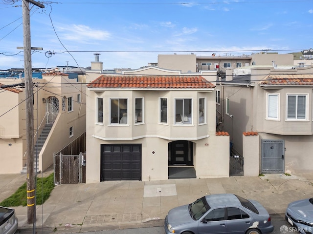 multi unit property with a tile roof, stucco siding, concrete driveway, an attached garage, and fence