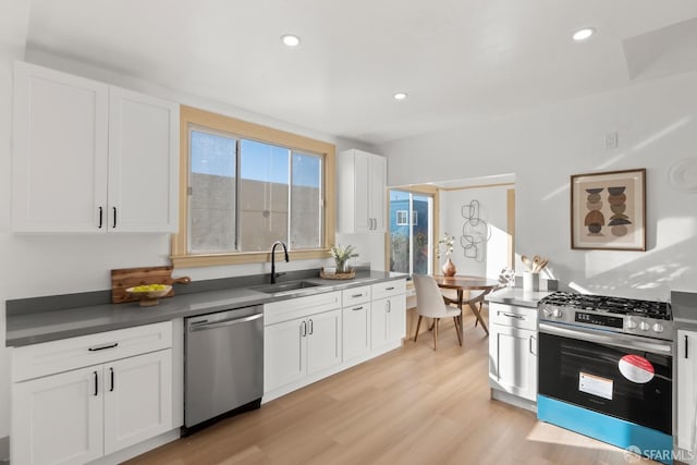 kitchen with white cabinets, appliances with stainless steel finishes, light wood-style floors, a sink, and recessed lighting