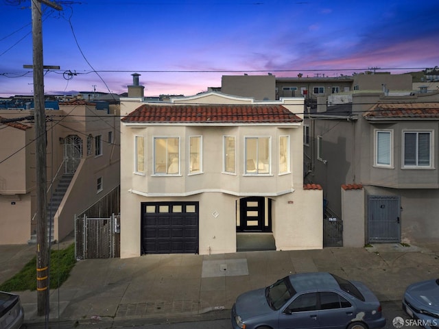 view of property with a tiled roof, driveway, and stucco siding