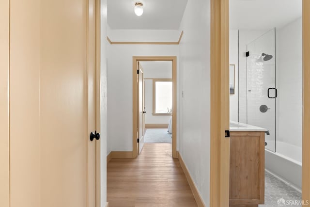 hallway featuring light wood-type flooring and baseboards