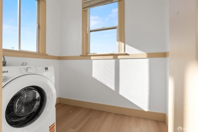 laundry room featuring baseboards, laundry area, washer / clothes dryer, and light wood-style floors
