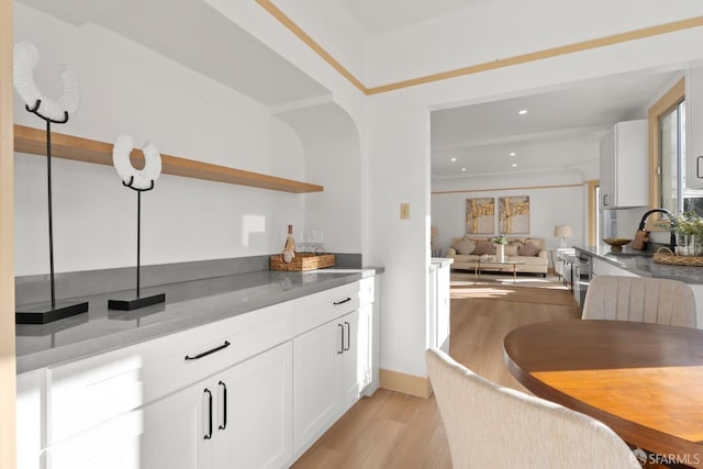 kitchen with a sink, white cabinetry, open floor plan, open shelves, and light wood finished floors