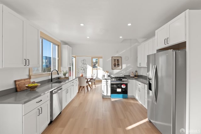 kitchen featuring light wood-type flooring, white cabinetry, appliances with stainless steel finishes, and a sink