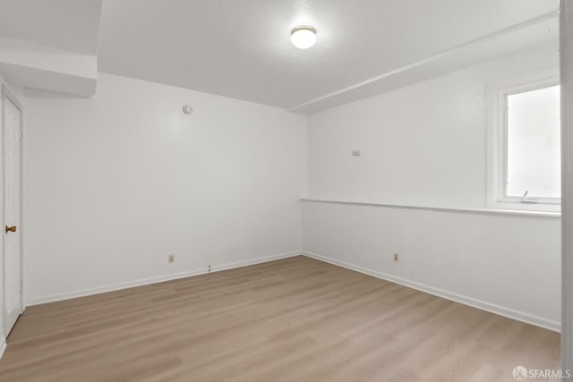 spare room featuring light wood-type flooring and baseboards