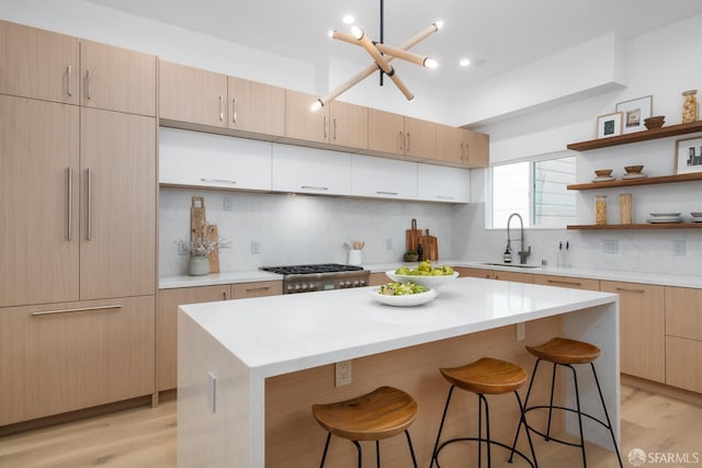 kitchen featuring backsplash, a kitchen breakfast bar, open shelves, and a sink