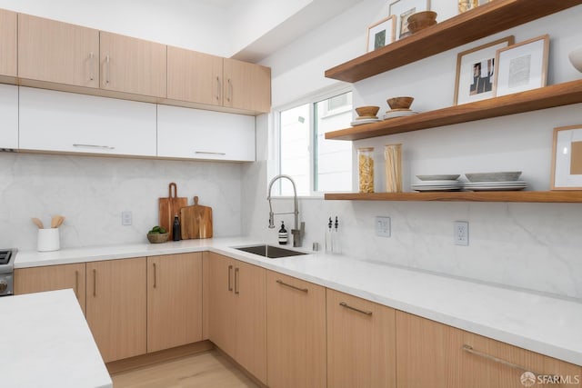 kitchen featuring a sink, backsplash, light countertops, and open shelves