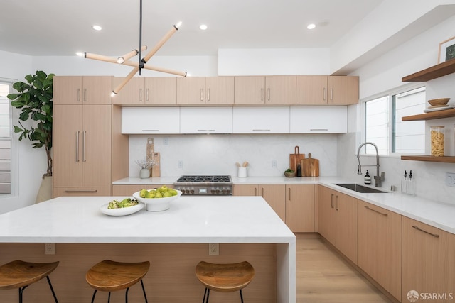 kitchen with a sink, open shelves, a breakfast bar, and light brown cabinetry