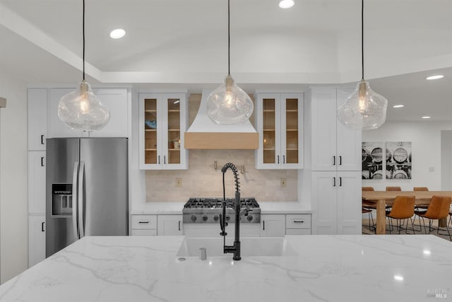 kitchen featuring white cabinetry, stainless steel fridge, custom range hood, and tasteful backsplash