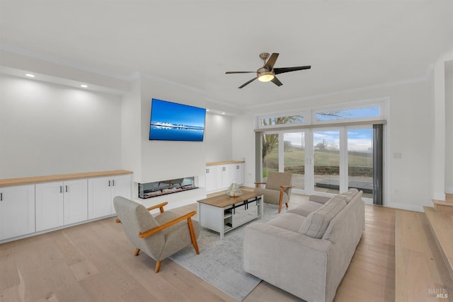 living room featuring ceiling fan, ornamental molding, a multi sided fireplace, and light hardwood / wood-style floors