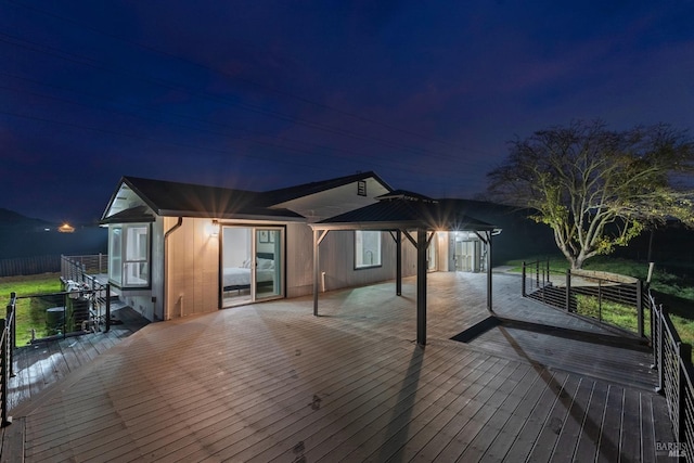 back house at night featuring a wooden deck