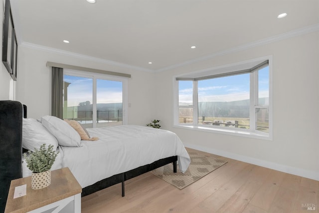 bedroom featuring light wood-type flooring, crown molding, and a mountain view