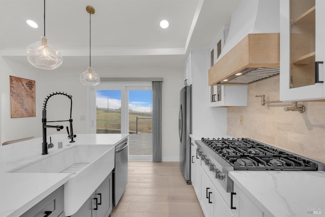 kitchen with appliances with stainless steel finishes, custom exhaust hood, white cabinets, and light stone countertops