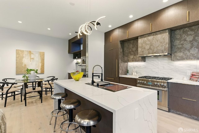4038 18th St, San Francisco, CA 94114 - kitchen with high end stainless steel range, light wood-style flooring, backsplash, recessed lighting, and a center island with sink