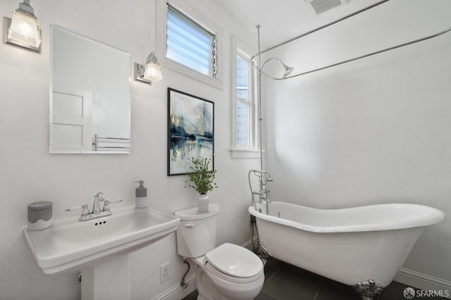 bathroom featuring tile patterned floors, toilet, and a tub