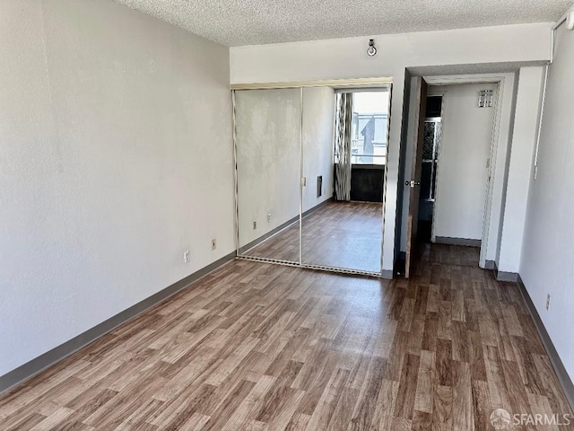 unfurnished bedroom featuring a closet, a textured ceiling, and hardwood / wood-style flooring