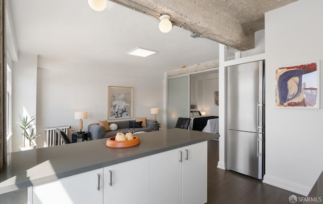 kitchen featuring white cabinets, kitchen peninsula, dark wood-type flooring, and stainless steel refrigerator