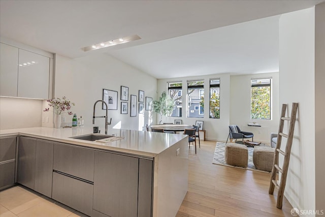 kitchen featuring gray cabinets, kitchen peninsula, sink, and light hardwood / wood-style flooring