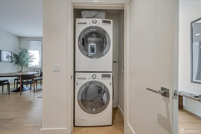 clothes washing area featuring stacked washing maching and dryer and light hardwood / wood-style floors