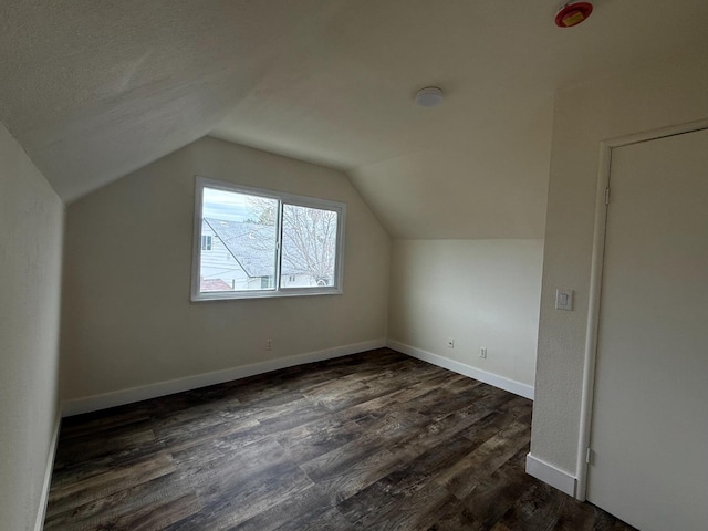 bonus room with vaulted ceiling, dark wood finished floors, and baseboards