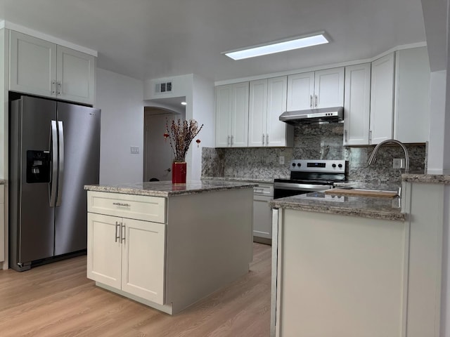 kitchen featuring stone counters, a center island, stainless steel appliances, visible vents, and under cabinet range hood