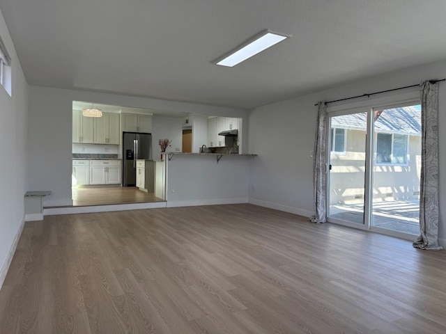 unfurnished living room featuring baseboards and light wood-style floors