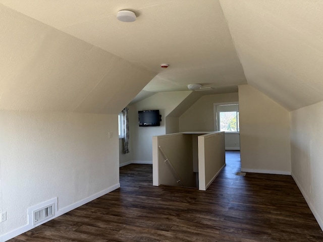 bonus room with dark wood-type flooring, visible vents, vaulted ceiling, and baseboards