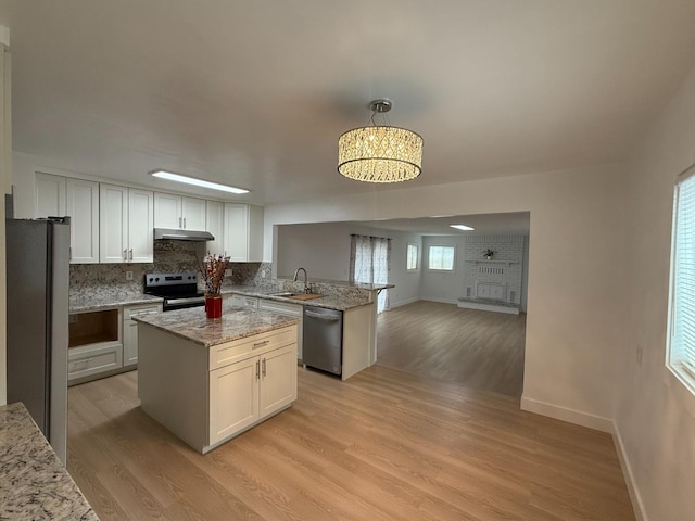 kitchen featuring a kitchen island, light stone counters, stainless steel appliances, white cabinetry, and pendant lighting